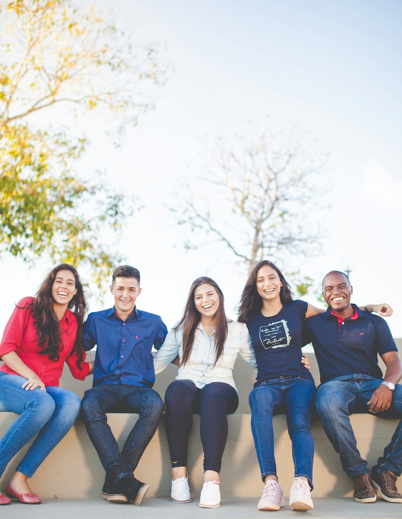 A group of smiling young people sitting together outdoors